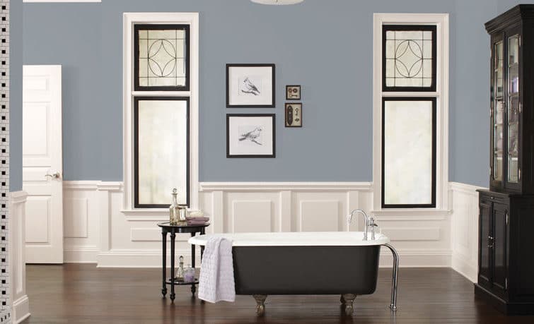 Painter cutting a clean line where a sage-gray wall meets a white ceiling